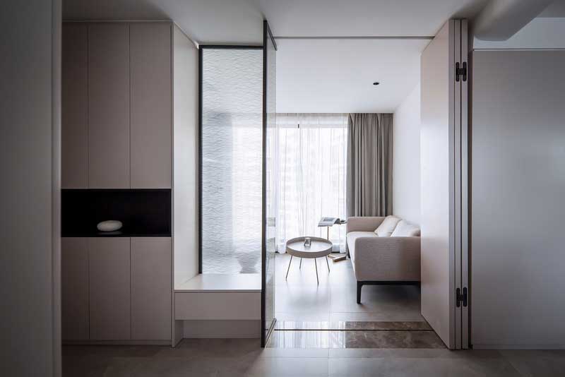 打破原有入戶花園格局限制 重新拆解再利用 利用頂天立地的鞋柜與折疊門結(jié)合，磨砂玻璃隔斷下的小臺(tái)子兼任換鞋凳的功能，光從磨砂玻璃隔斷透出來(lái)，即滿足儲(chǔ)物需求，又為女業(yè)主從事地產(chǎn)行業(yè)需要在家辦公筑建一個(gè)多功能的空間，營(yíng)造一個(gè)開(kāi)闊又多變的開(kāi)敞交互的家。